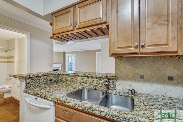 kitchen with backsplash, ornamental molding, white dishwasher, a sink, and light stone countertops