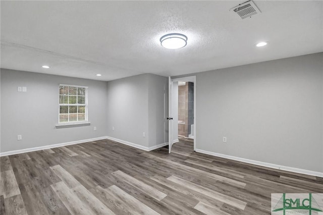 empty room with recessed lighting, visible vents, a textured ceiling, wood finished floors, and baseboards