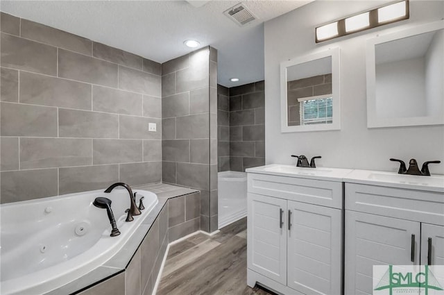 full bath featuring visible vents, a sink, a whirlpool tub, and wood finished floors