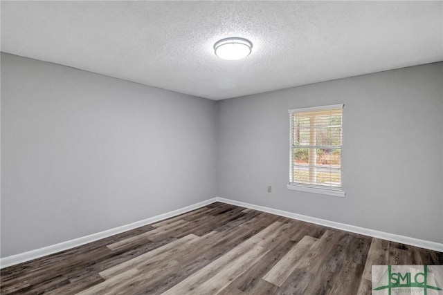 spare room with dark wood-style floors, baseboards, and a textured ceiling