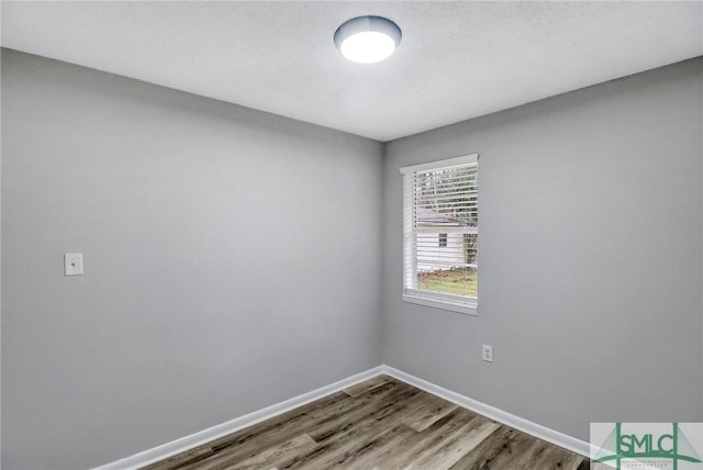 spare room featuring baseboards and wood finished floors