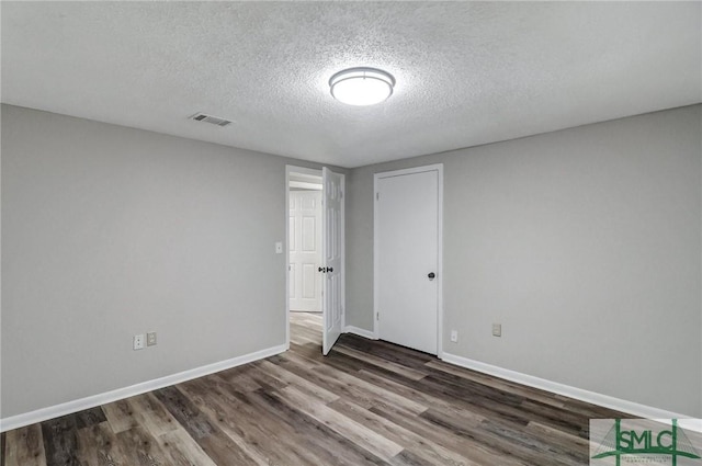 empty room featuring baseboards, a textured ceiling, visible vents, and wood finished floors