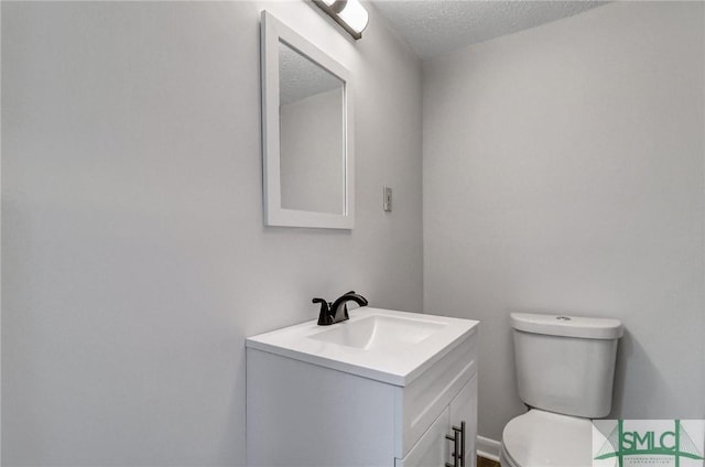 bathroom with toilet, a textured ceiling, and vanity