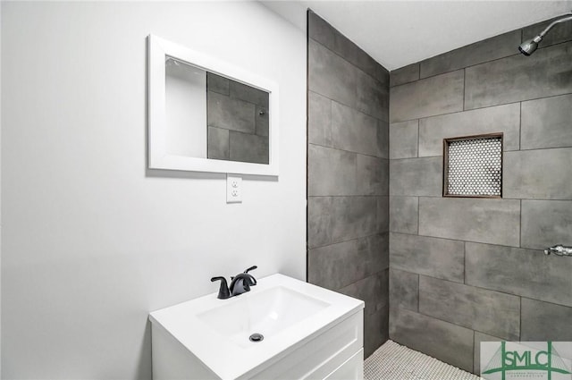 full bath featuring a tile shower and vanity