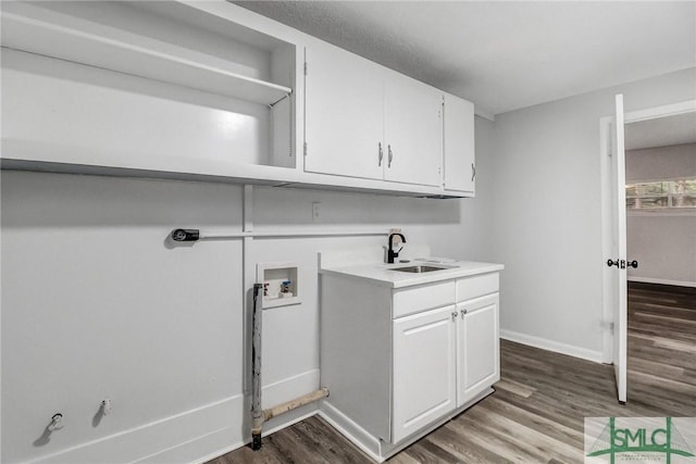 clothes washing area with washer hookup, a sink, baseboards, and wood finished floors