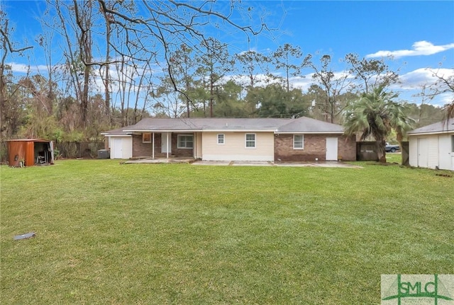 back of house featuring an outbuilding, a patio, brick siding, a yard, and a shed