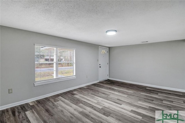 unfurnished room featuring baseboards, a textured ceiling, and wood finished floors