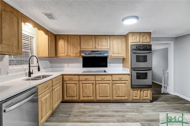 kitchen featuring appliances with stainless steel finishes, light countertops, a sink, and under cabinet range hood