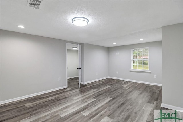 empty room featuring recessed lighting, visible vents, a textured ceiling, wood finished floors, and baseboards