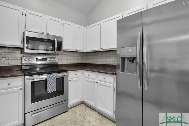 kitchen with tasteful backsplash, white cabinets, dark stone counters, stainless steel appliances, and light tile patterned flooring