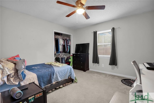 carpeted bedroom featuring ceiling fan, a closet, baseboards, and a textured ceiling