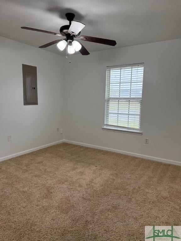 carpeted empty room with ceiling fan, electric panel, and baseboards