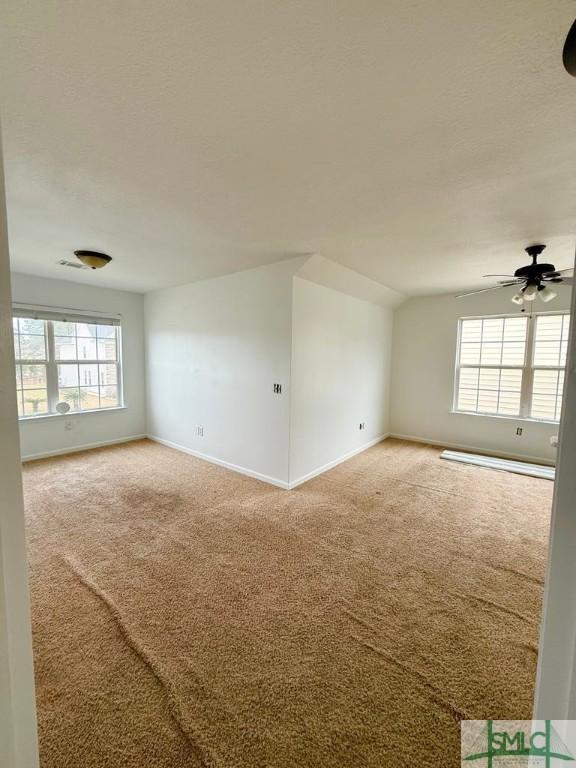 spare room with vaulted ceiling, plenty of natural light, carpet flooring, and baseboards