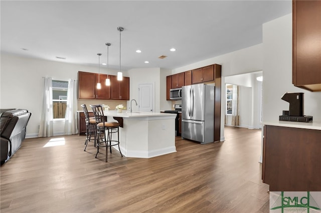 80 Rimmon Ct, Richmond Hill, GA 31324 - kitchen with light countertops, appliances with stainless steel finishes, open floor plan, wood finished floors, and a kitchen breakfast bar