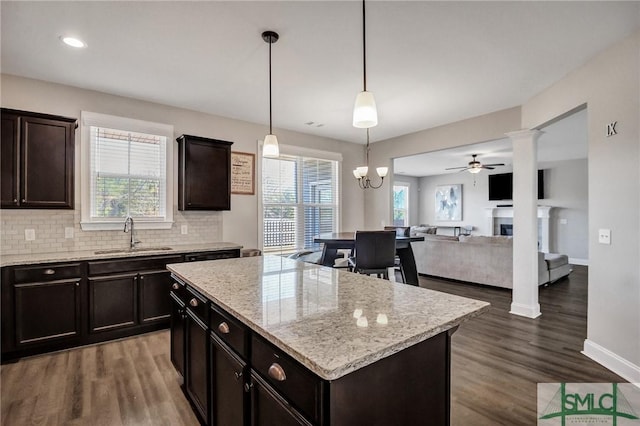 kitchen featuring a fireplace, a sink, backsplash, and wood finished floors