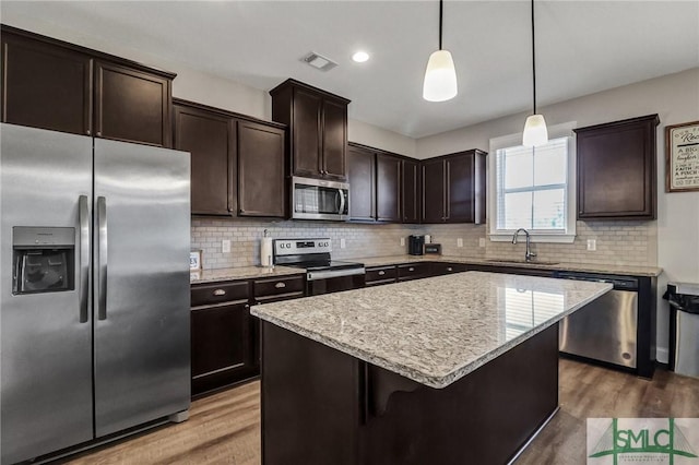 kitchen with stainless steel appliances, wood finished floors, a sink, and dark brown cabinetry