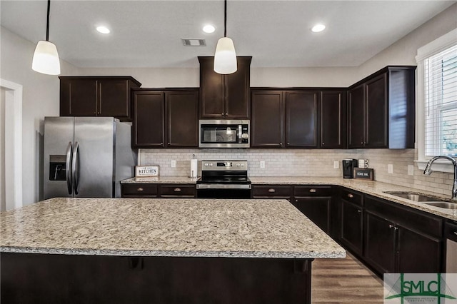 kitchen featuring a sink, visible vents, hanging light fixtures, appliances with stainless steel finishes, and decorative backsplash