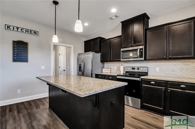 kitchen with appliances with stainless steel finishes, decorative backsplash, dark wood-type flooring, and a center island