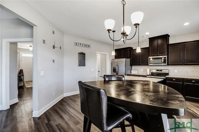 kitchen featuring dark wood-style flooring, baseboards, dark brown cabinets, appliances with stainless steel finishes, and tasteful backsplash