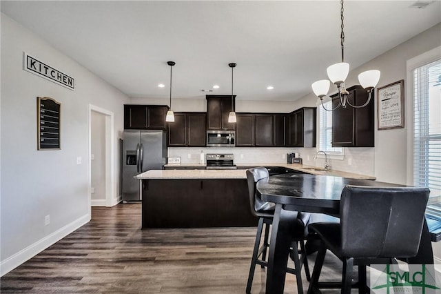 kitchen with dark brown cabinetry, a sink, appliances with stainless steel finishes, tasteful backsplash, and dark wood finished floors