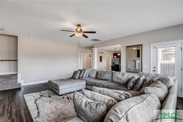 living room featuring baseboards, visible vents, ceiling fan, dark wood-type flooring, and stairs