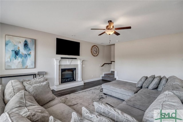 living area with baseboards, ceiling fan, stairway, wood finished floors, and a high end fireplace