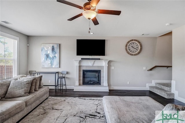 living area with wood finished floors, visible vents, baseboards, stairs, and a glass covered fireplace