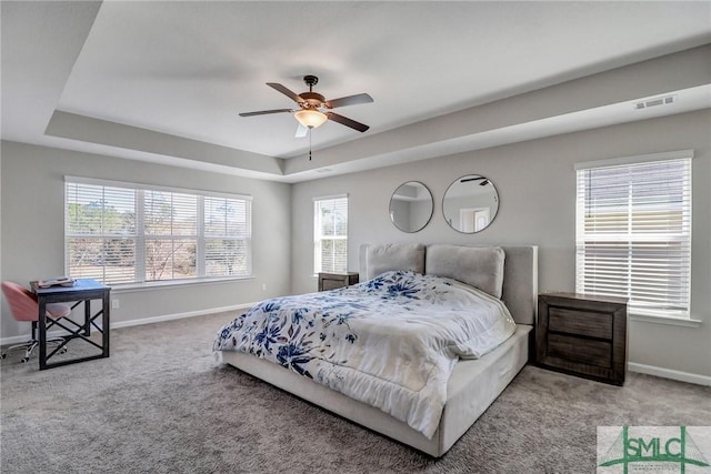 bedroom with a tray ceiling, carpet, and baseboards