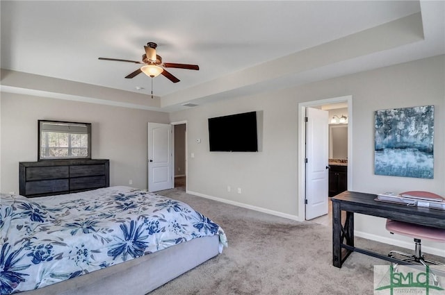 bedroom with carpet, a raised ceiling, a ceiling fan, connected bathroom, and baseboards