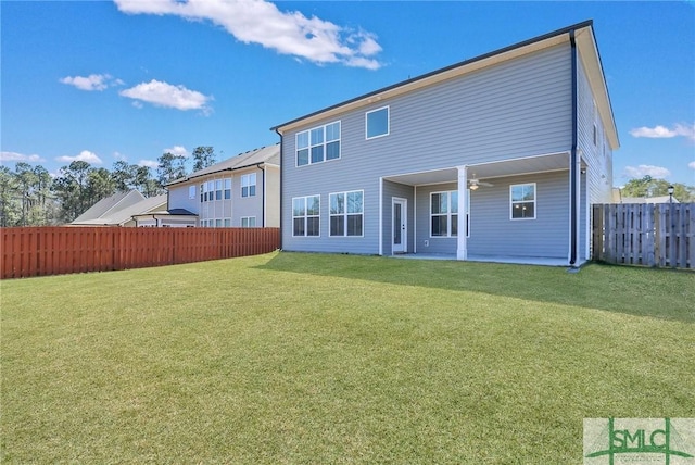 rear view of property featuring ceiling fan, a lawn, and a fenced backyard