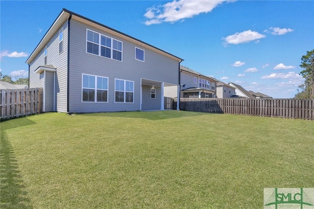 rear view of property with a fenced backyard and a yard