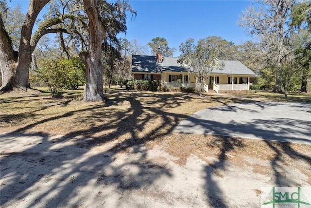 rear view of property featuring covered porch and driveway