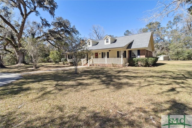 view of front of house featuring an outbuilding, a shed, covered porch, and a yard