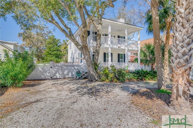 view of front facade featuring a balcony, a gate, fence, and covered porch