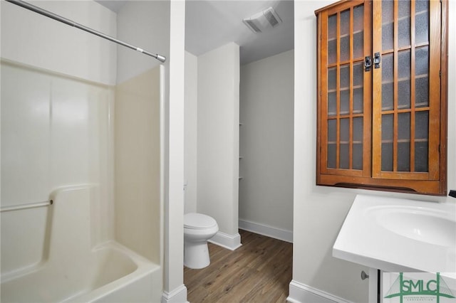 bathroom featuring visible vents, shower / bathing tub combination, toilet, wood finished floors, and baseboards