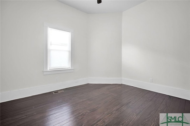 spare room featuring baseboards, visible vents, ceiling fan, and dark wood-type flooring