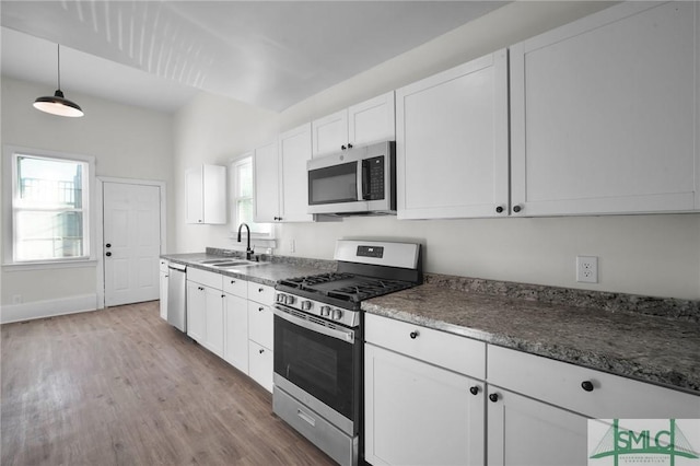 kitchen with white cabinetry, appliances with stainless steel finishes, a sink, and wood finished floors