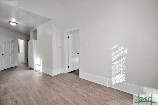 unfurnished room with light wood-type flooring and baseboards