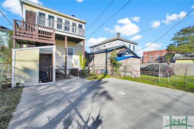 rear view of house with fence and a balcony