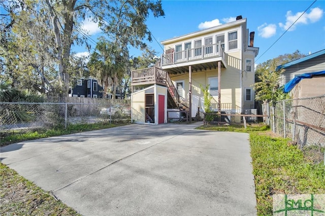 view of front facade with fence private yard, a chimney, stairway, and an outbuilding