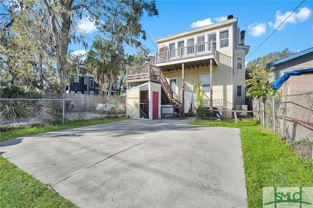 view of front of home featuring stairs, a chimney, an outbuilding, and fence private yard