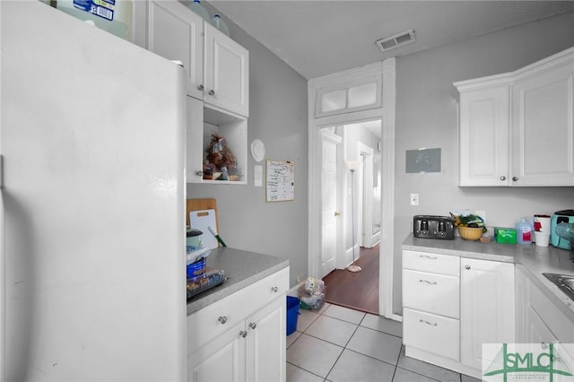 kitchen with visible vents, white cabinets, freestanding refrigerator, light countertops, and light tile patterned flooring