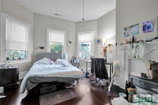 bedroom with dark wood-style flooring, visible vents, and baseboards