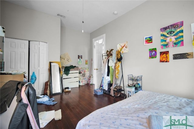 bedroom with a closet, wood finished floors, and visible vents