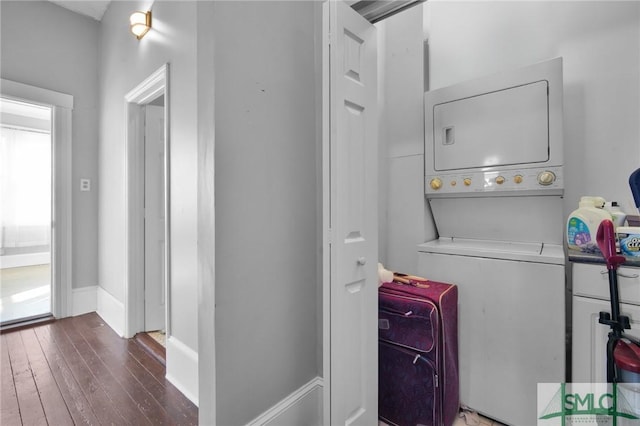 washroom featuring stacked washer and clothes dryer, baseboards, hardwood / wood-style floors, and laundry area