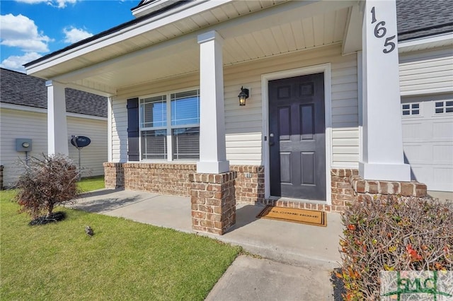 property entrance featuring brick siding, a shingled roof, covered porch, a lawn, and a garage