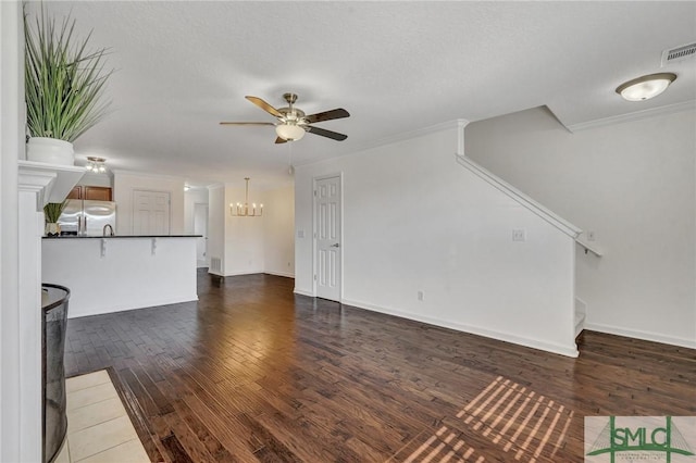 unfurnished living room featuring dark wood-style floors, visible vents, ornamental molding, baseboards, and ceiling fan with notable chandelier