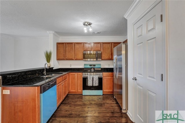 kitchen with appliances with stainless steel finishes, dark stone countertops, dark wood-type flooring, crown molding, and a sink