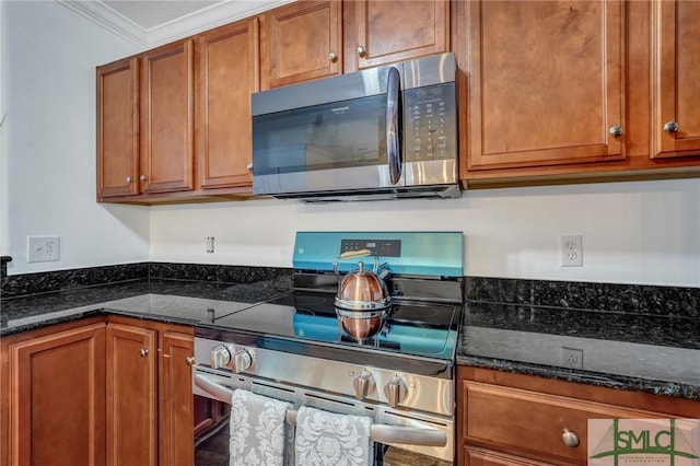 kitchen featuring stainless steel appliances, dark stone counters, brown cabinets, and ornamental molding