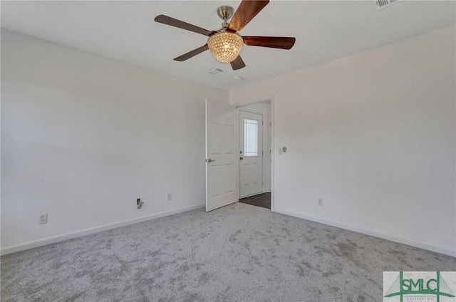 carpeted spare room featuring ceiling fan and baseboards